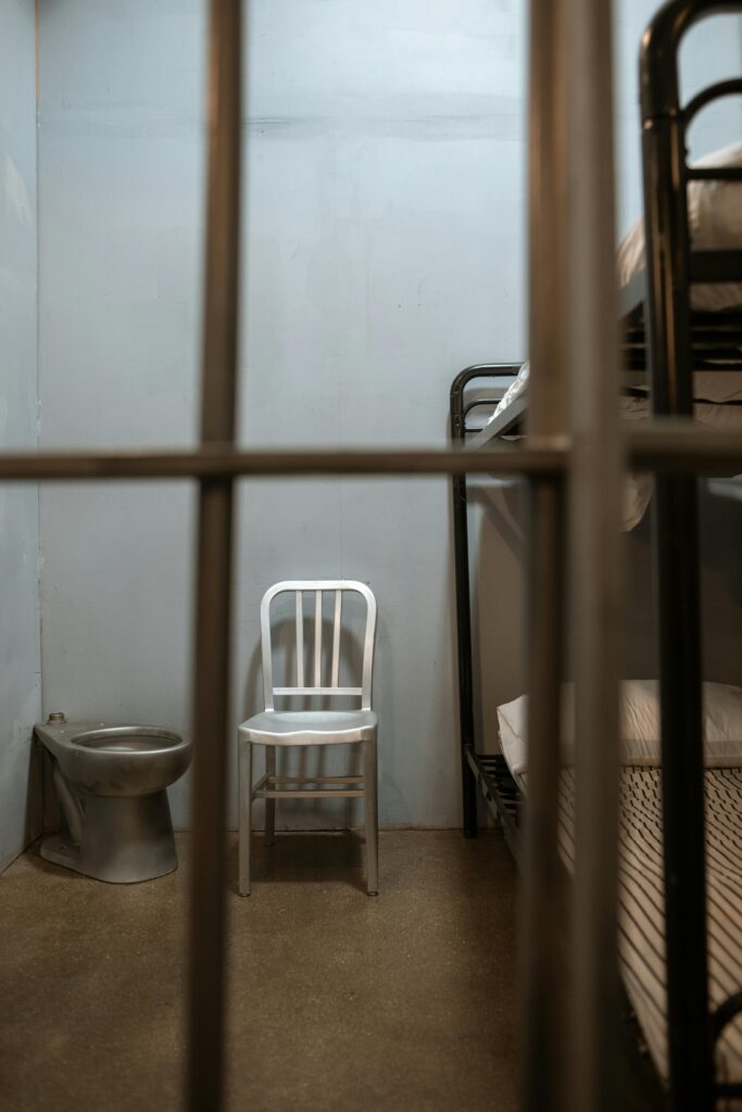 Double Deck Bed Near Metal Chair and Bowl Behind Bars