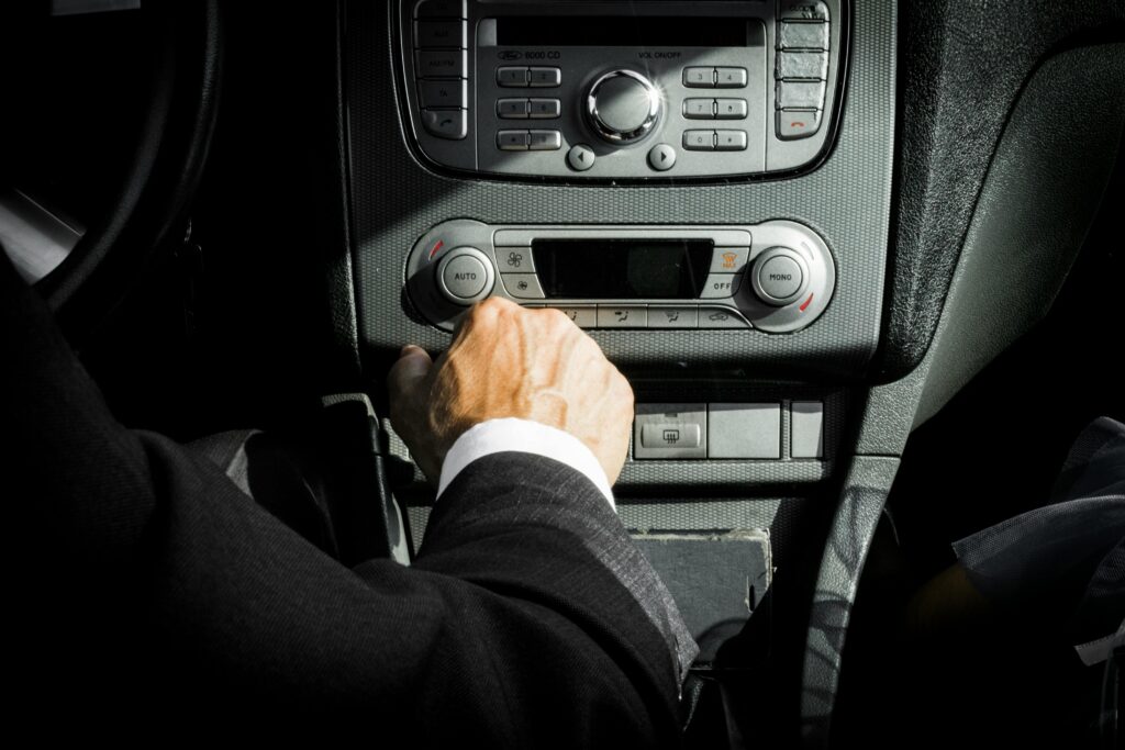 Close-up of a driver in a suit operating the car dashboard controls, capturing a professional interior setting.