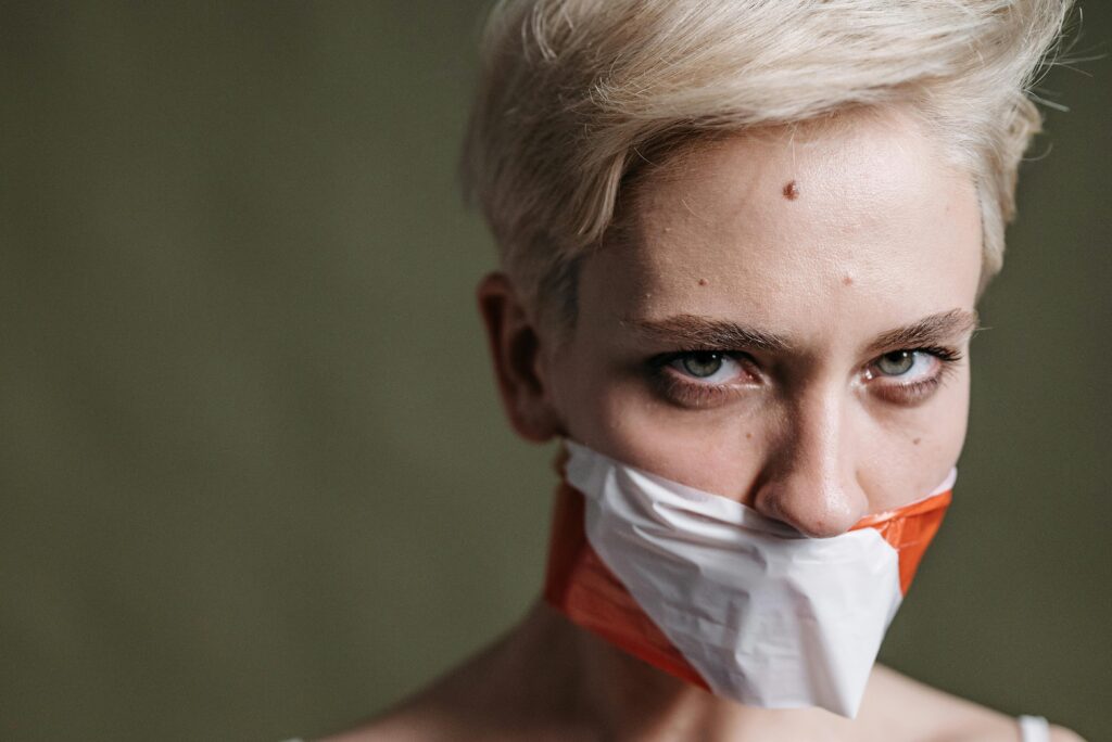 A defiant woman with taped mouth symbolizes silenced voices and human rights.