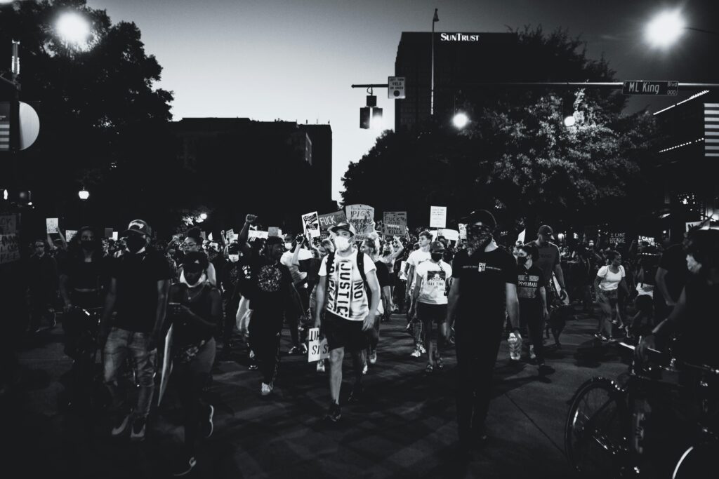 pexels-photo-4552854-4552854-1 Black and white photo of a large protest march on city streets at night.